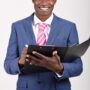 Portrait of black businessman wearing suit and tie smiling on white background with a black folder in his hands. Studio shot